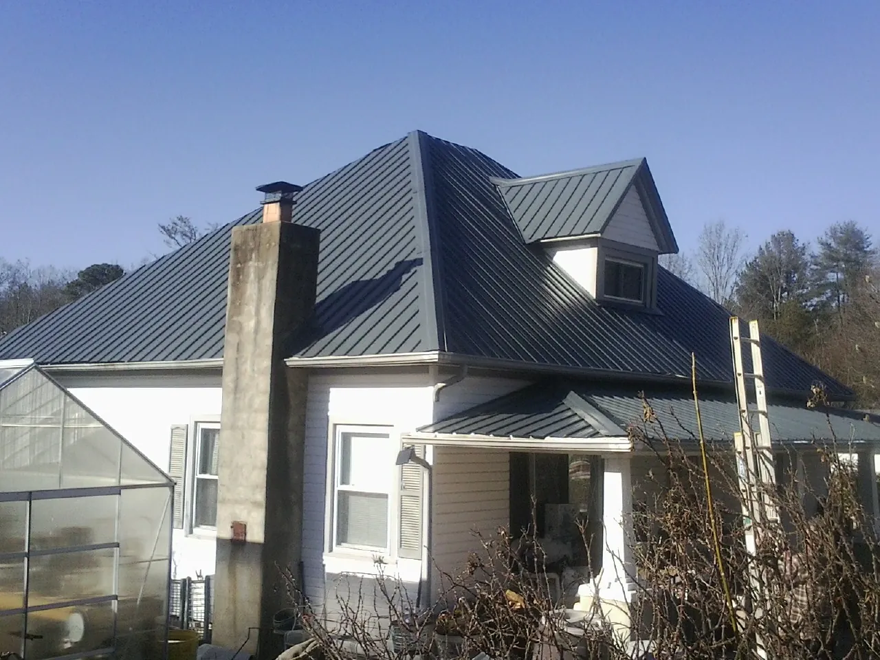 Dark blue standing seam metal roof on a white farmhouse with dormer — Slate & Tile Roof Repair by Roofing Brothers in Galloway