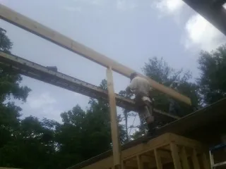 Carpenter setting a ridge beam over a new addition frame — Ice Dam Removal by Roofing Brothers in Galloway
