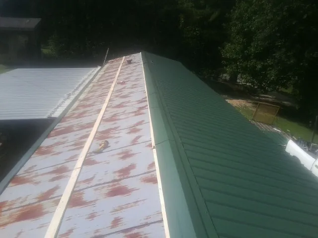 Old rusted panels beside newly installed green metal roofing — Wind Damage Roof Repair by Roofing Brothers in Galloway