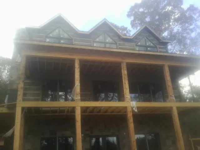 Dormers and porch framing on a large log home under construction — Roof Coating work by our crew in Galloway