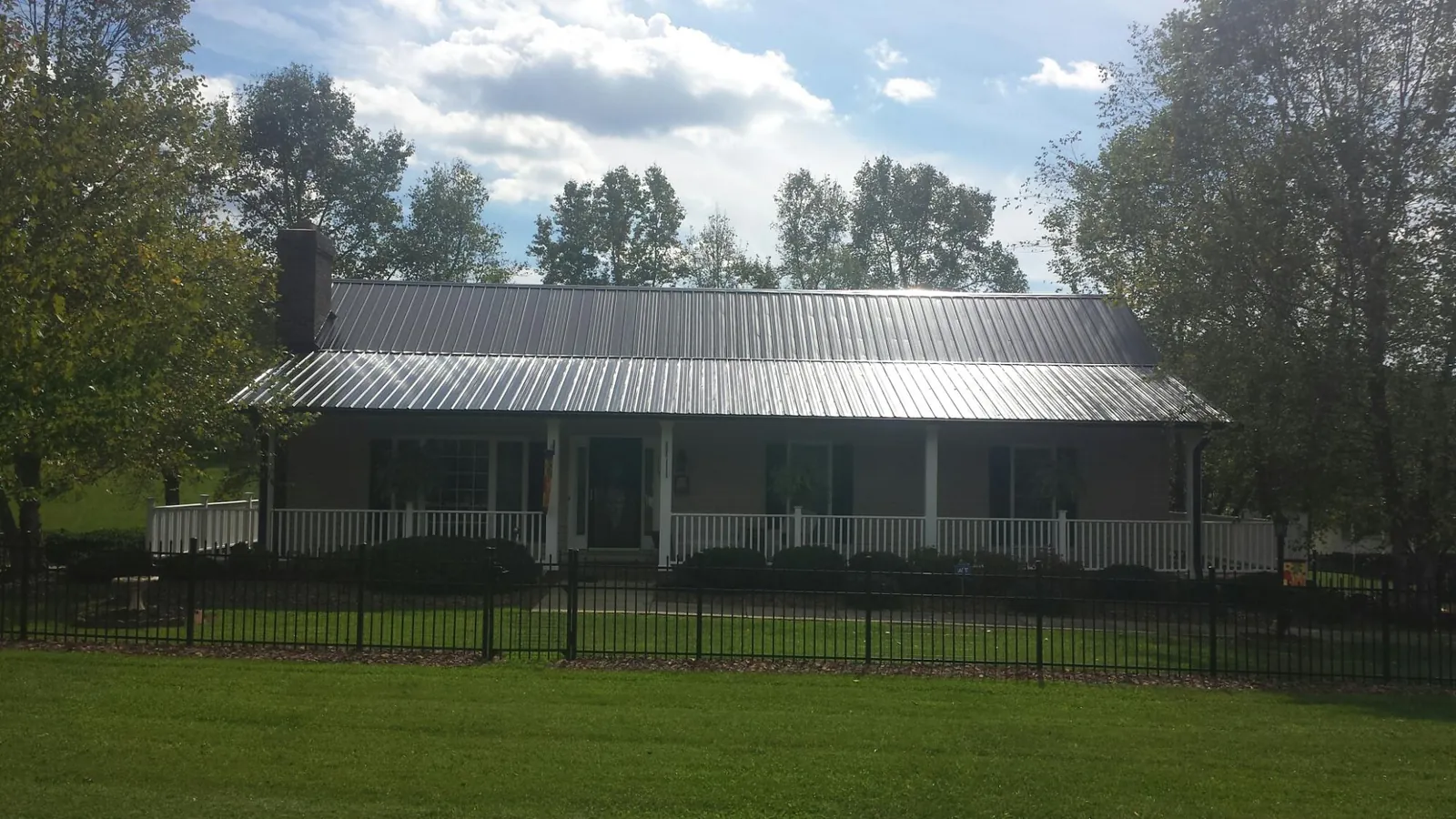 Gray metal roof on a brick ranch with a full width front porch — Gutter Guard Installation work by our crew in Galloway