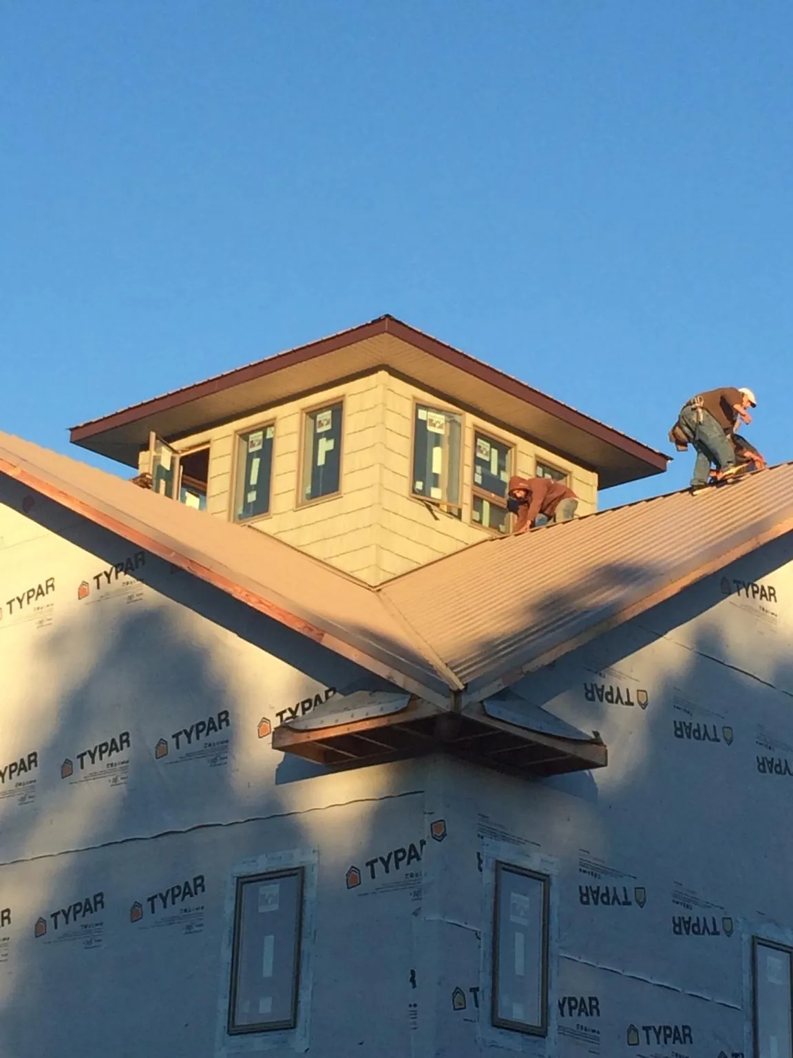 Roofers working around a rooftop cupola on a new metal roof at sunset — Roof Waterproofing in Galloway by Roofing Brothers